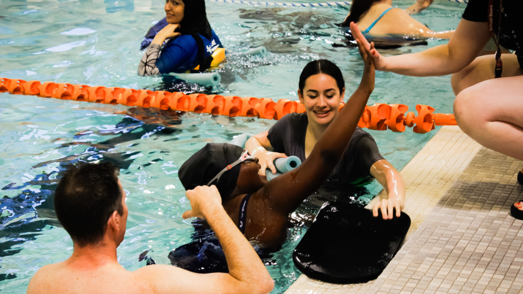 A swimming competitor arriving and giving a high five at the end of the swim