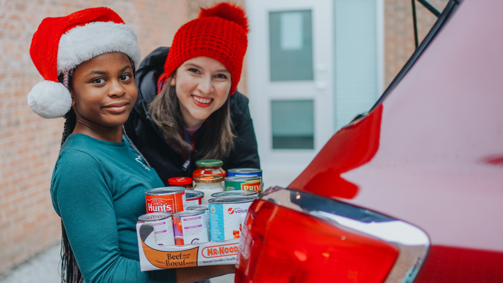 St. Mary's student with teacher putting food supplies in the car trunk